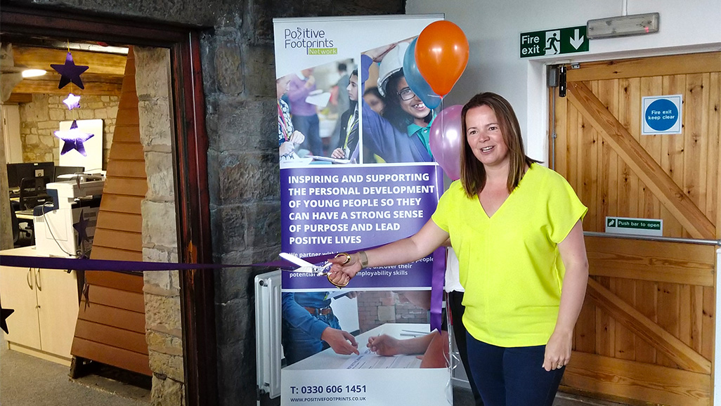 photo of Lesley Burrows cutting a ribbion for our new office grand opening