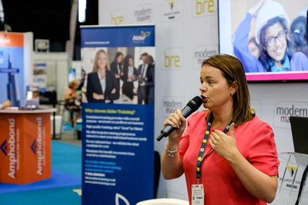 Lesley Burrows speaking at a Positive Footprints event holding a microphone