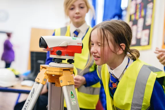 Girl looking into a range finder wearing a high vis jacket