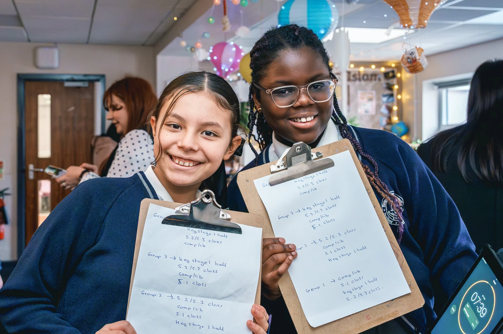 Two pupils smile and hold up clipboards as they run the event